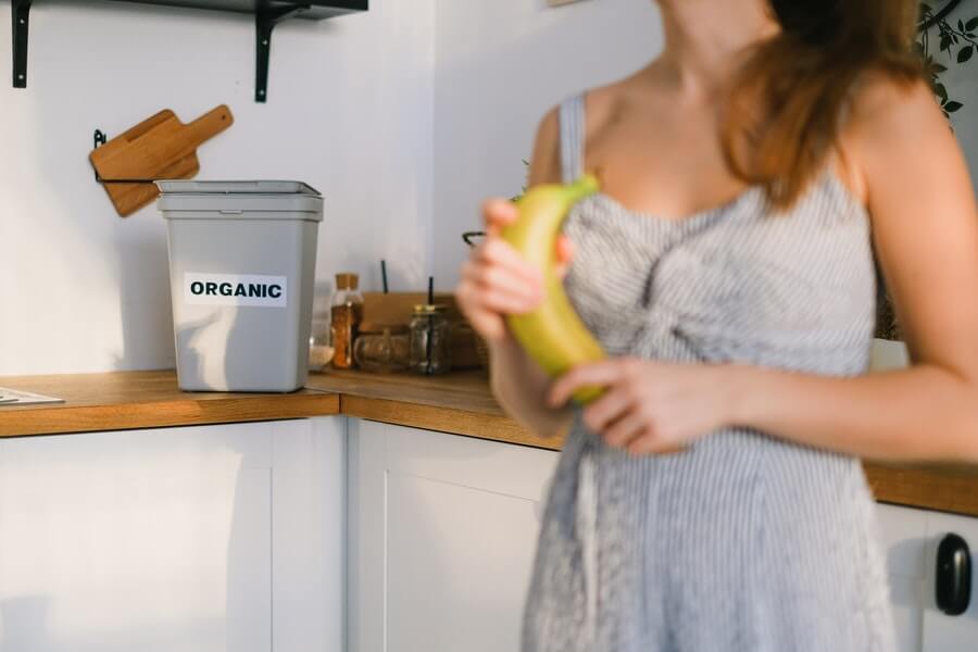 woman adding to a compost bin for sustainable gardening