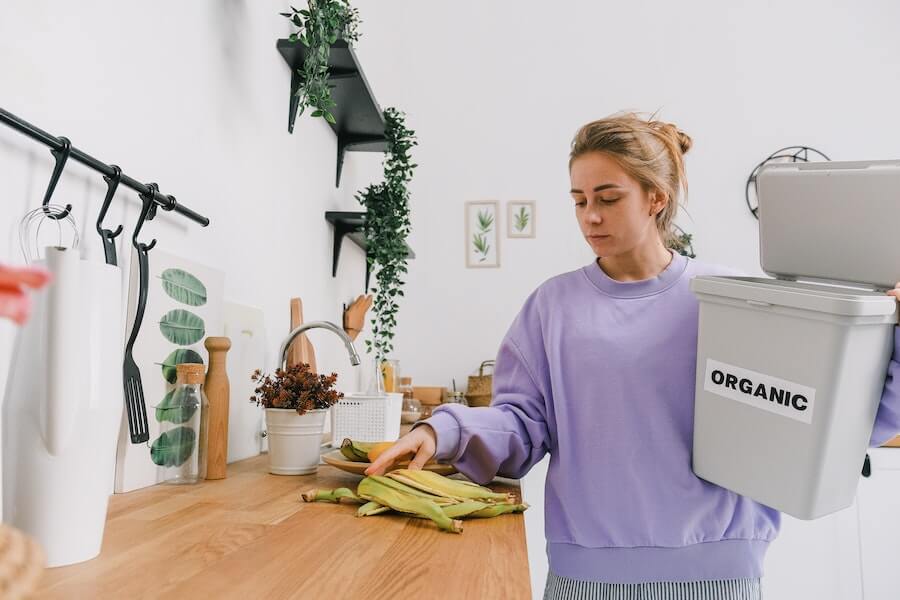 a woman showing how to reduce food waste with an organic bin