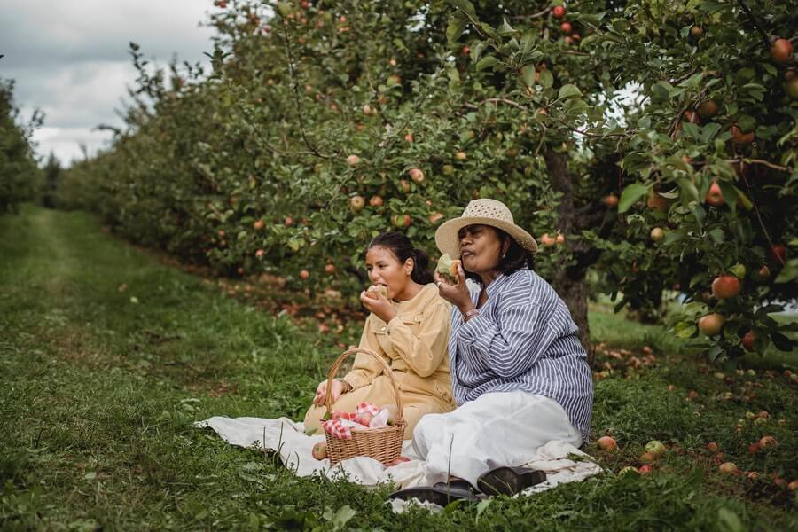 two women eating in a fruit tree guild